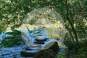 stepping stones in the water near some trees and rocks on the side of a river