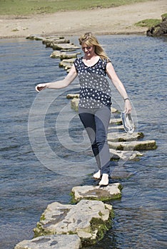 Stepping stones woman barefoot walking across river