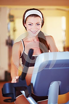 Stepping towards fitness. Portrait of a fit young woman using a treadmill at gym.