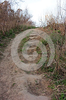 Steps built into a slope or dig up on a hill. Stairs in sloping ground. A stairway and path in the park, wood or forest.