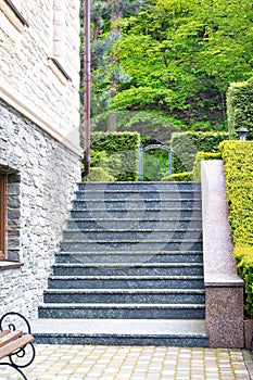 The steps of the granite staircase rise up along the wall of the beautiful estate and trimmed boxwood bushes