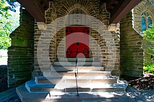 Steps Leading Up to a Red Door on a Cobblestone Church In a Covered Driveway