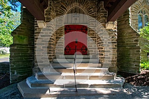 Steps Leading Up to a Red Door on a Cobblestone Church In a Covered Driveway