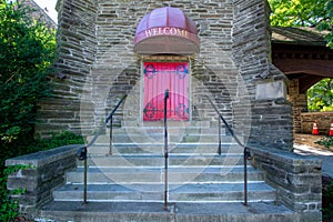 Steps Leading Up to a Red Door on a Cobblestone Church With a Welcome Sign Above the Door