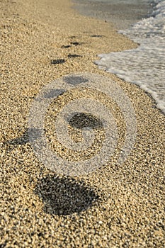 Steps in the sand next to the clear blue sea