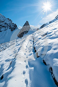 Steps in snow in wild mountains on a sunny day, Alps, France