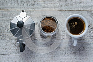 Top view of moka - italian coffee maker and coffee cup on wooden white background