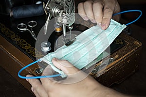 Stepwise stitching of blue fabric medical masks. Close-up hands holding a ready-made mask. The concept of medical mask deficiency photo