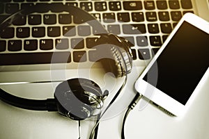 Stereo headphones , mobile phone and the keyboard of a computer , Online music , download song on mobile