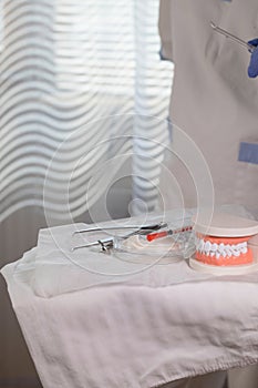 Sterile cotton napkins, human jaw model and stomatological tools on a table. Closeup