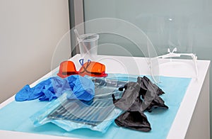 Sterile medical instruments in packaging and blue and black disposable gloves