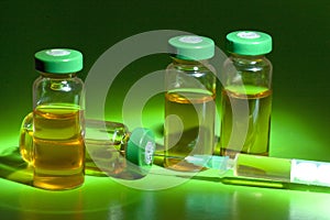 Sterile medical vials with medication solution, ampoules, and syringe on a green background