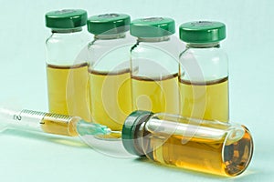 Sterile medical vials with medication solution, ampoules, and syringe on a light blue background