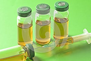 Sterile medical vials with medication solution, ampoules, and syringe on a light green background