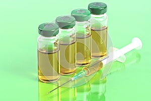 Sterile medical vials with medication solution, ampoules, and syringe on a light green background