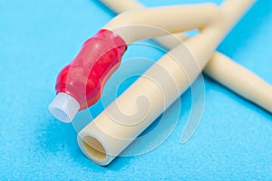 Sterile silicone-elastomer coated latex Foley urinary catheter  with balloon port and drainage port isolated on blue background