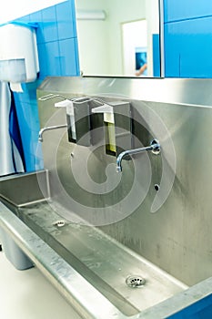 Sterile steel washbasin in modern surgery room.