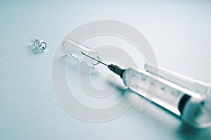 Sterile syringe with a needle and an ampoule of medicine on a blue background. treatment, prevention, laboratory, infection. photo