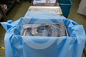 a sterilization department in a hospital, cleaned instruments are wrapped in a blue cloth before the container is sterilized