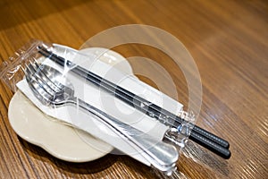 Sterilized cutlery,chopsticks spoon fork with paper napkin,securely packed in clear plastic bag placed on a plate,ready for serve