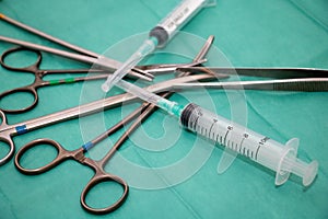 Sterilized surgical instrument on green fabric background. Surgeon doctor tool and syringe