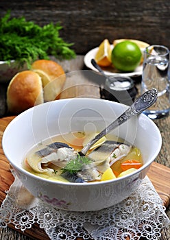 Sterlet fish soup with vegetables on wooden background.