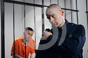 A stern, bald prison warden makes the rounds of the cells and transmits information over the radio to the head of the photo