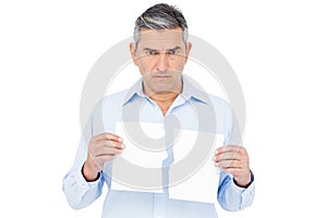 Stern man holding ripped paper