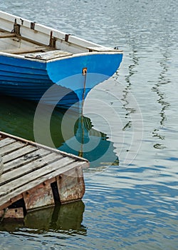 The stern of an old wooden boat moored at the pier, and reflection