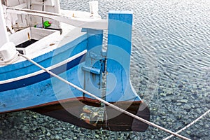 The stern of a wooden boat with a rudder and a propeller in the clear water of the Adriatic sea photo