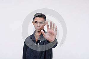 A stern young Filipino man harshly rejects an offer, looking displeased. Gesturing with an open palm. Isolated on a white