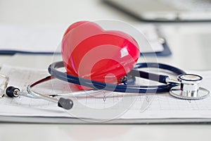 Stethescope and red heart lying on cardiogram photo