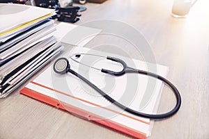 Stethoscope with black medical clipboard.