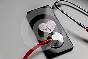 Stethoscope and black smartphone with a heart symbol and heartbeat to show digital doctors office, digital diagnosis