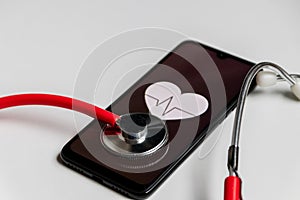 Stethoscope and black smartphone with a heart symbol and heartbeat to show digital doctors office, digital diagnosis