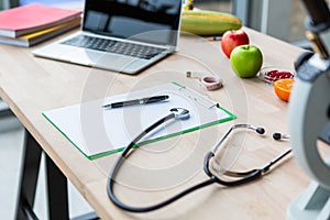 Stethoscope and blank note paper with labtop on nutritionist doctor table in laboratory room