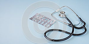 Stethoscope, on a blue background.An empty packet of pills. Greeting background.