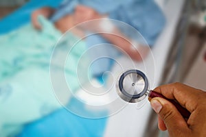 Stethoscope with of blur image of A patient in the hospital with saline intravenous, in Asian elderly man hand.