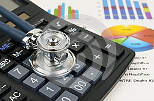 Stethoscope and calculator on charts and graphs. Finance, statistics and investments.