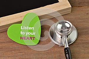 Stethoscope, chalkboard and love shape written with LISTEN TO YOUR HEART