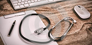 Stethoscope with clipboard by keyboard and mouse on table