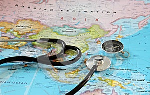 A stethoscope and a compass on a world map.