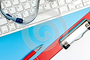 Stethoscope on computer keyboard on blue background.