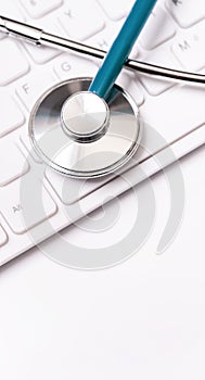 Stethoscope on computer keyboard on white background. Physician write medical case long term care treatment concept, close up,