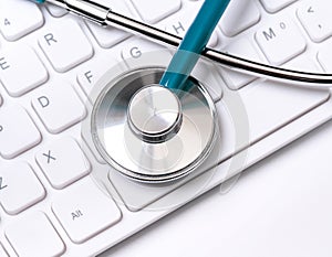 Stethoscope on computer keyboard on white background. Physician write medical case long term care treatment concept, close up,