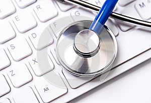 Stethoscope on computer keyboard on white background. Physician write medical case long term care treatment concept, close up,