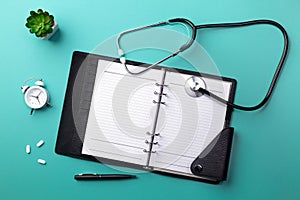 Stethoscope in doctors desk with notebook, keyboard, mouse, glasses, syringe, ampoules, inhaler and pills