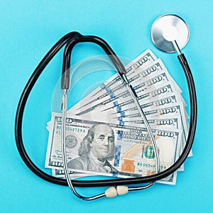 Stethoscope and dollar bills on blue background