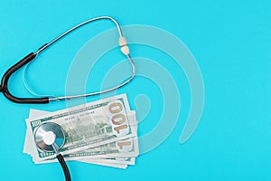 Stethoscope and dollar bills on blue background.