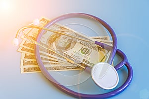 Stethoscope and dollar bills on blue background. Mock-up with copy space for your text. Concept of health care costs and